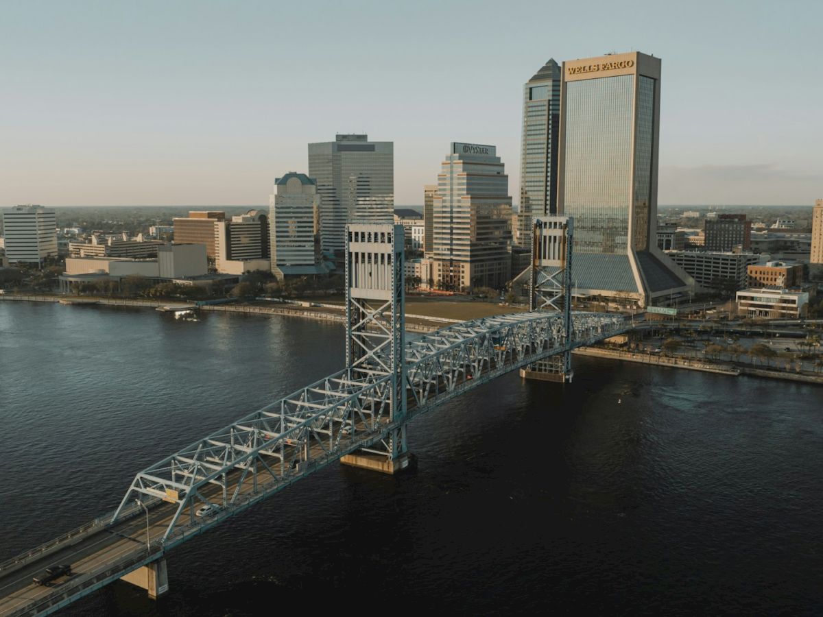 A cityscape featuring a river, a prominent bridge, and tall buildings, including one marked 