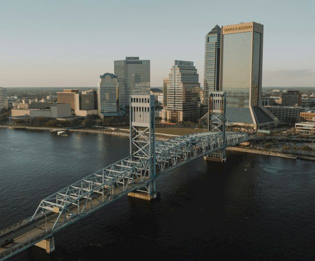 An image of a city skyline featuring a tall bridge over water with buildings in the background during daytime can be seen.